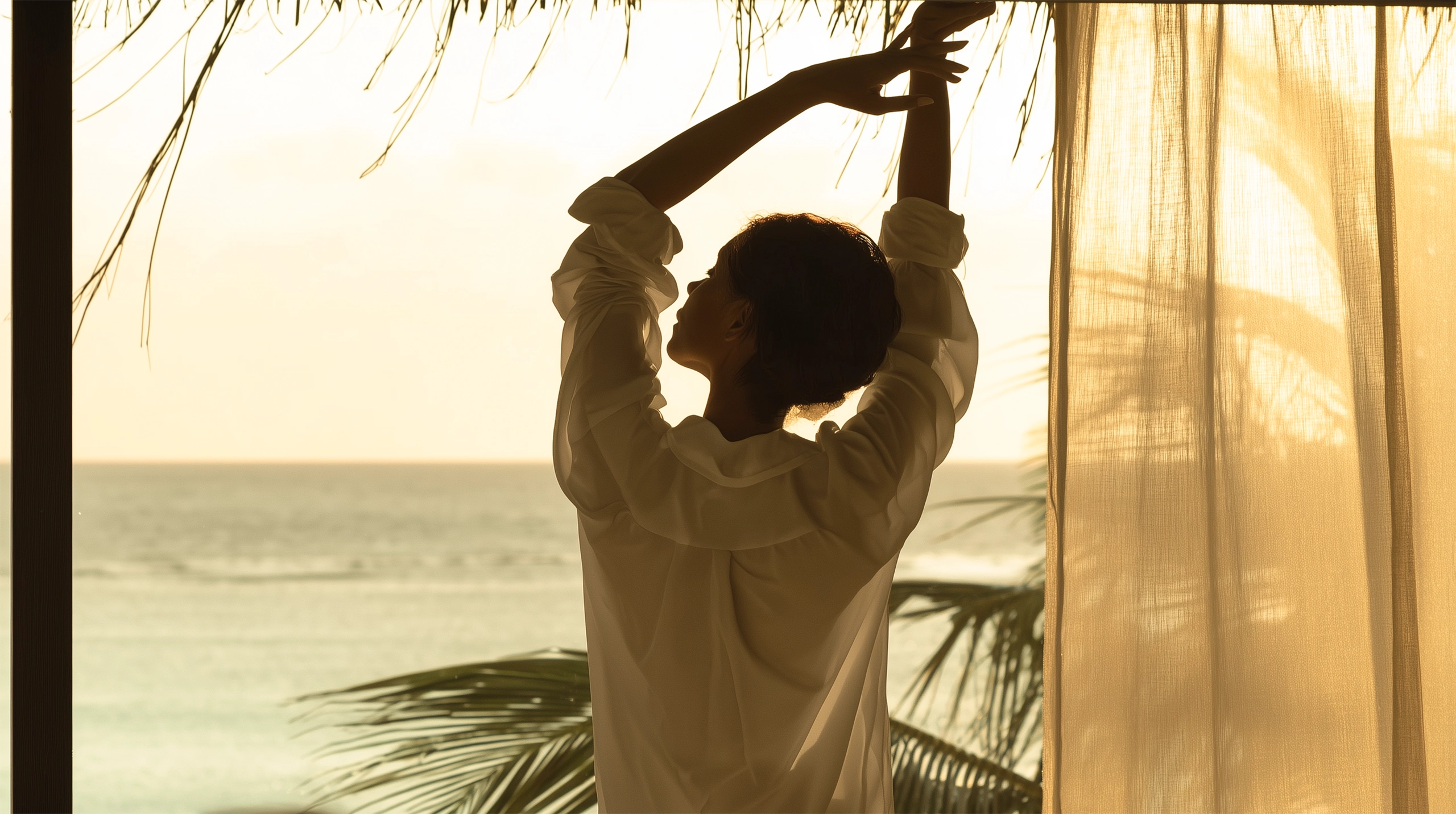 Woman stretching from hotel window looking at the ocean water